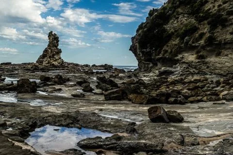 Sharp and rough cliff rocks emerging from the water of the Australian coast line Foto stock