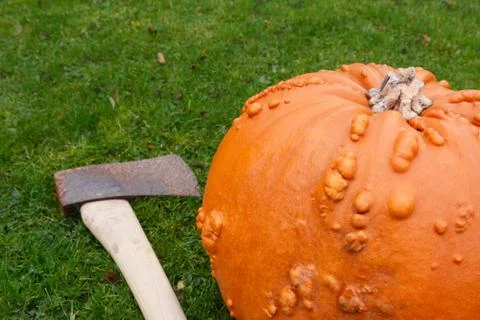 Sharp axe on grass with orange pumpkin Foto stock