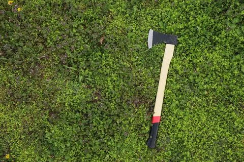 Sharp axe on green grass in forest, top view Stock Photos