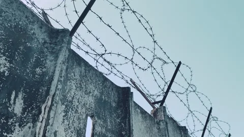 Sharp barbed wire along the concrete wall perimeter of prison or concentration Stock-Footage 303352106