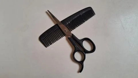 Sharp barber scissors resting on a black plastic comb Stock Photos
