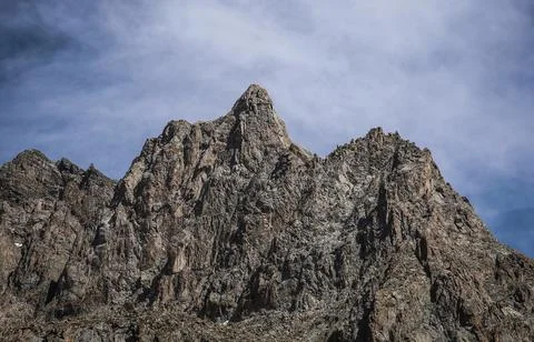 A sharp bare mountain peak against a clear blue sky Stock Photos