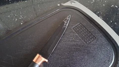 Sharp black kitchen knife with copper detail on cutting board Stock Photos