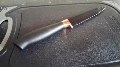 Sharp black kitchen knife with copper detail on cutting board Stock Photos