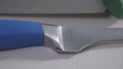 Sharp, blue handled knife on a white surface; pan Stock Footage 64027839