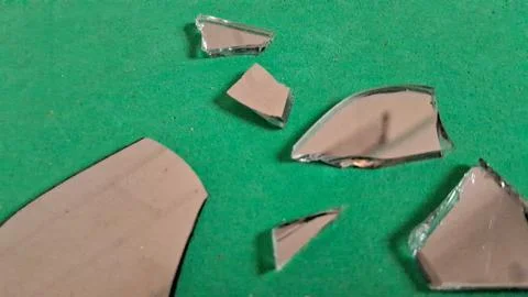 Sharp broken mirror shards scattered on a bright green surface Stock Photos