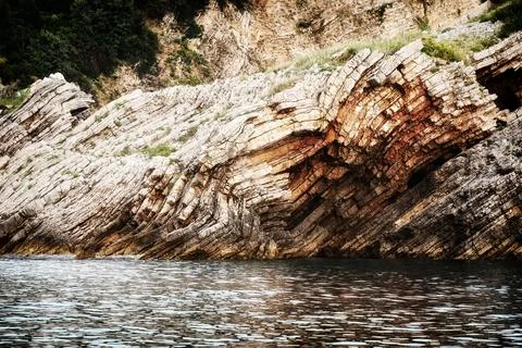 Sharp cliff and mountains cut close to the dark sea water Stock Photos