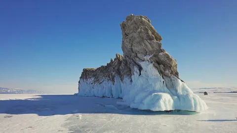 Sharp cliff covered with frozen ice. Huge gray lion-like rock. Sunshine blue sky Stock Footage 166461835