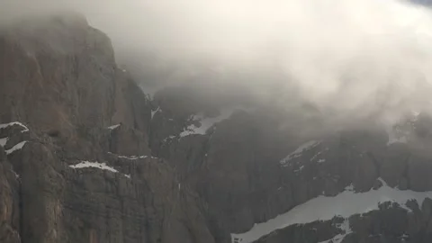 Sharp cliff peak rises from snowy rocky high - Covered Cliff and High Elevation Stock Footage 339375448
