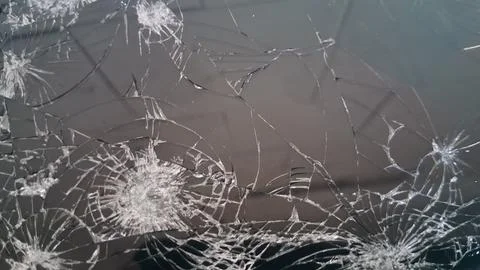 Sharp cracks spread across the dark surface of broken glass screen Stock Photos