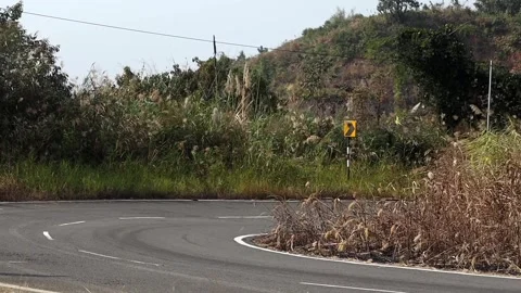 Sharp Curve Warning Sign on Rural Hillside Road Stock Footage 329839999