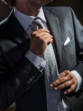 Sharp dressed businessman adjusting his necktie. Stock Photos