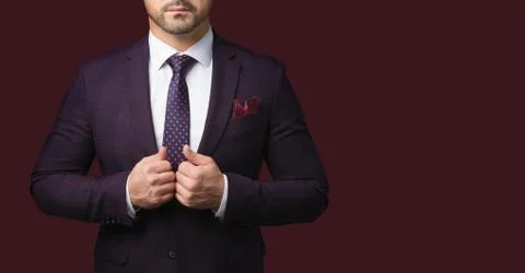 Sharp dressed man wearing jacket and tie isolated on dark red background. Stock Photos