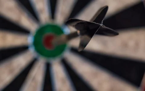 Sharp focus on a dart hitting the bullseye on a dartboard representing succ.. Stock Photos