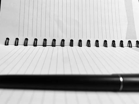 Sharp Focus Spiral Notebook Binding Blurred Pen Foreground Black and White Macro Stock Photos