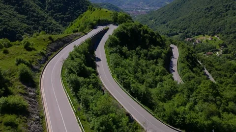 Sharp forest road switchback seen from overhead among green hills near Selvino Stock Footage 313586598