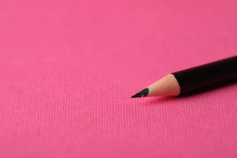 Sharp graphite pencil on pink background, closeup. Space for text Stockfoto's