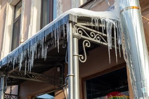 Sharp icicles a lot, melted snow hanging from eaves of roof, ownpipe. Frosty day Foto stock