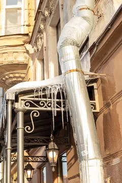 Sharp icicles a lot, melted snow hanging from eaves of roof and downpipe Stock Photos