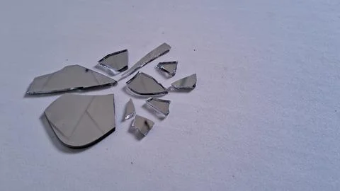 Sharp jagged fragments of a broken mirror on white surface Stock Photos