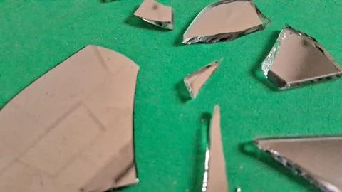 Sharp jagged fragments of a broken mirror on green background Stockfoto's