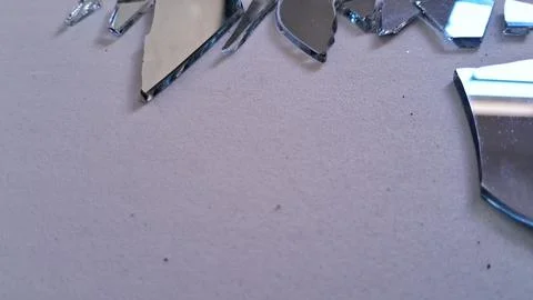 Sharp jagged pieces of broken mirror scattered on textured gray surface Stock Photos