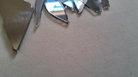 Sharp jagged pieces of broken mirror reflecting light on surface Stock Photos
