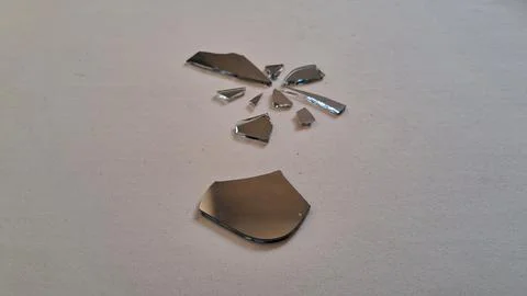 Sharp jagged pieces of broken mirror scattered on white surface background Stock Photos