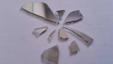 Sharp jagged pieces of a broken mirror on white surface Fotos de archivo