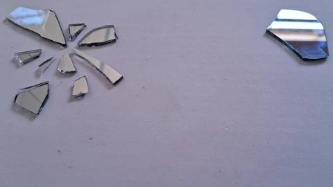 Sharp jagged pieces of broken mirror scattered on white surface texture Stock Photos