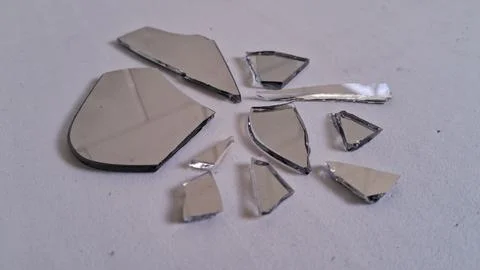 Sharp jagged pieces of a broken mirror on white surface Stock Photos