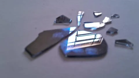Sharp jagged pieces of broken mirror reflecting bright window light indoors Stock Photos