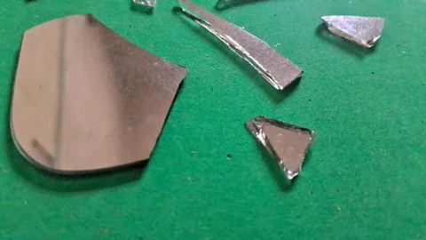 Sharp jagged pieces of broken mirror reflecting on green foam surface Stock Photos