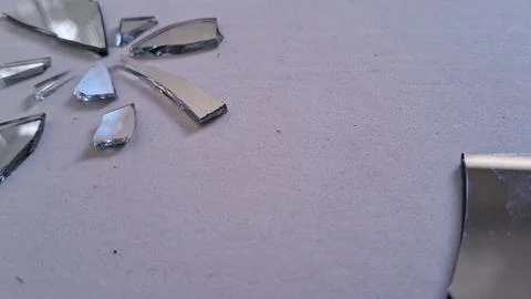 Sharp jagged shards of broken silver mirror on textured background Stock Photos