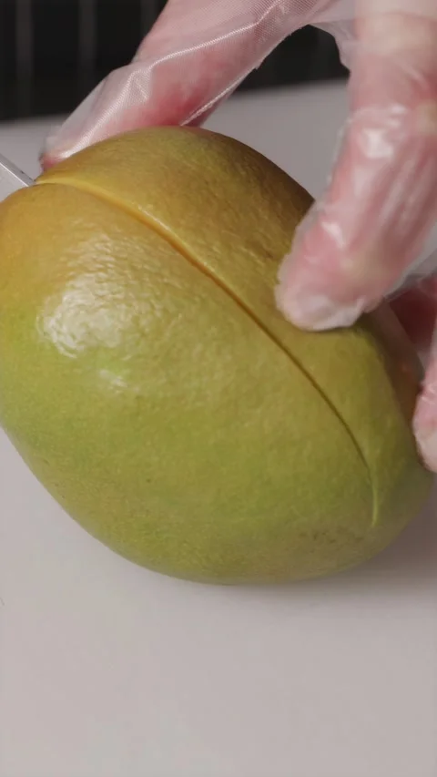 Sharp kitchen knife cutting a ripe juicy mango fruit in half Stock Footage 337119201