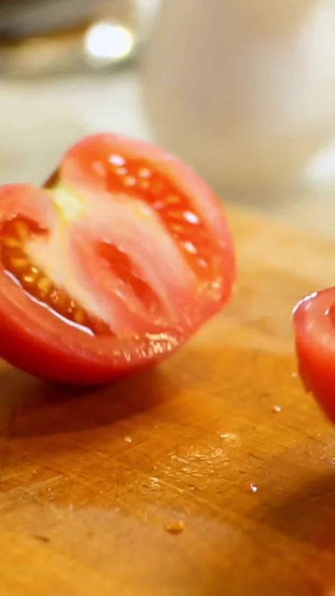 Sharp kitchen knife slices fresh red tomato into halves Stock Footage 334169671