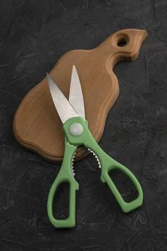 Sharp kitchen scissors on a wooden cutting board in the kitchen Stock Photos