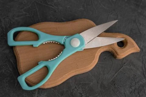 Sharp kitchen scissors on a wooden cutting board in the kitchen Stock Photos