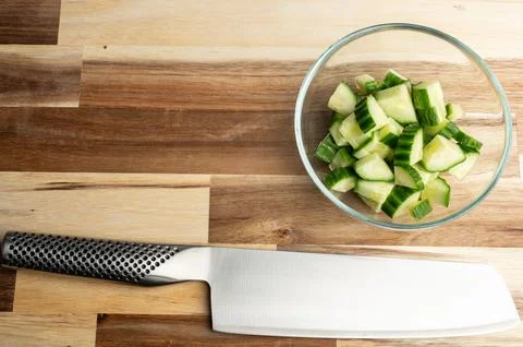 Sharp knife and chopped cucumbers on wooden countertop Foto stock