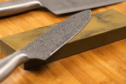Sharp knife and sharpening stone on a wooden cutting board. Stock Photos