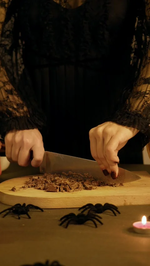 Sharp knife crushes chocolate bar into chunks on a board, table is decorated for 스톡 동영상 318935666