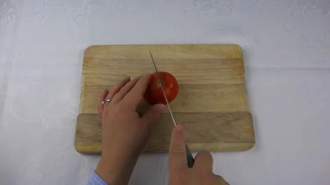 A sharp knife cuts a red tomato into four pieces Stock Footage 95809282