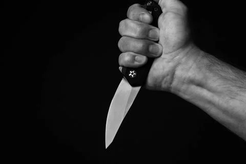 A sharp knife in the man's hand. The use of cold weapons. Knife attack . Ar.. Stock Photos