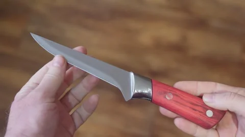A sharp knife with a metal blade and wooden handle held in hands. Stock Footage 300565188