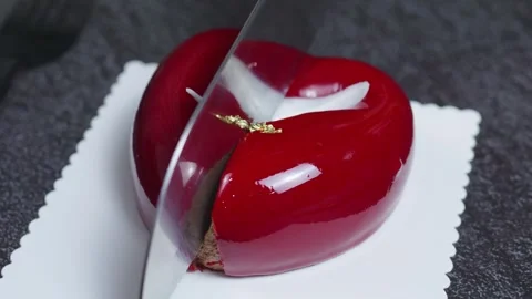 Sharp knife slicing glossy raspberry chocolate mousse cake, exposing layered Stock Footage 314893897