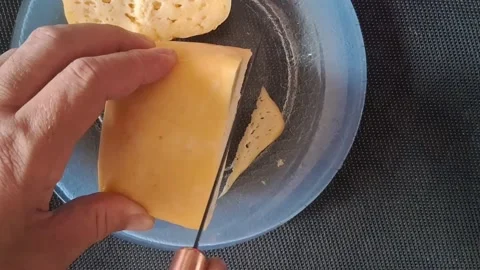 Sharp knife slicing yellow cheese block in motion video footage Stock Footage 339335055