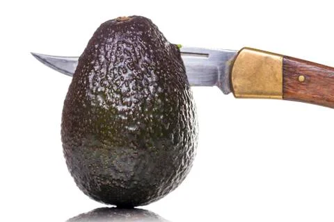 Sharp knife  stings through an avocado, isolated on white Foto stock