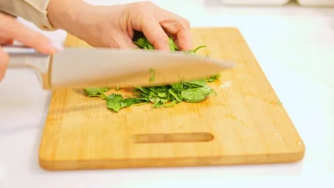 Sharp knife swiftly cuts through fresh greens on board. With each movement knife Stock Footage 272447349
