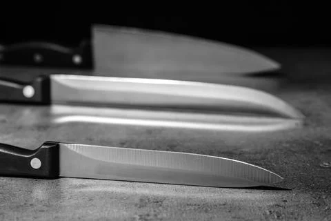 Sharp knives on table against dark background Stock Photos