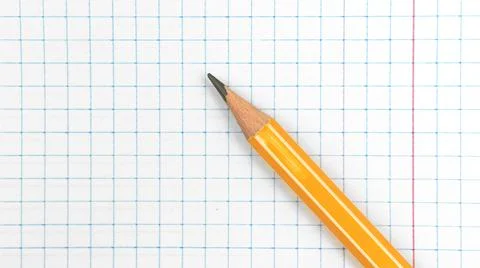Sharp lead pencil school stationery on a checkered notebook background, close Stock Photos